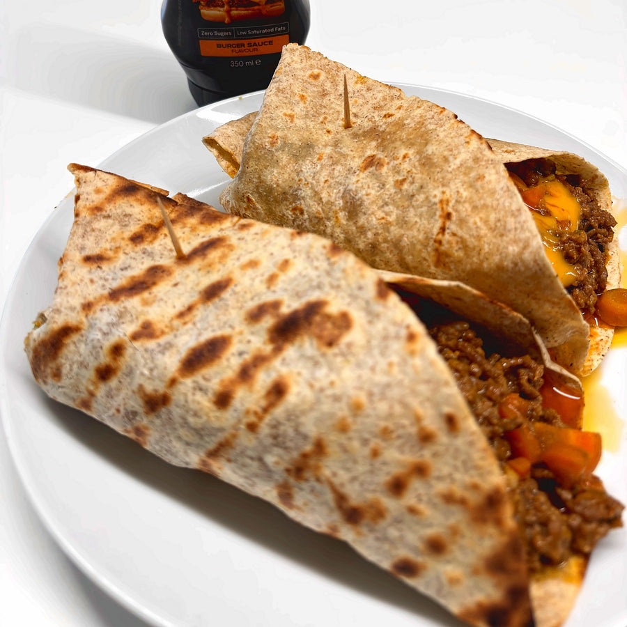 Two grilled wholegrain wraps with minced beef, carrots and melted cheese, next to a zero-sugar burger sauce